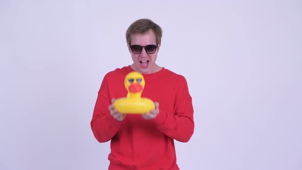 Happy Young Handsome Man Holding Inflatable Duck and Giving Thumbs Up