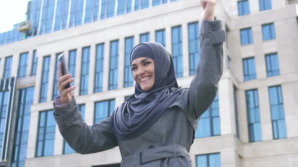 Excited Muslim Girl Reads Message on Phone About Job Hiring or Entering College