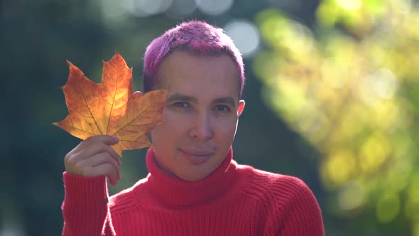 Young Gay Is Posing Outdoors, Smiling and Holding Dry Leaf of Maple, Closeup Portrait of Homosexual