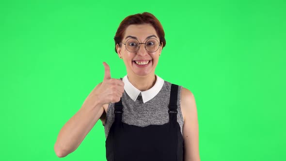 Portrait of Funny Girl in Round Glasses Is Showing Thumbs Up, Gesture Like. Green Screen