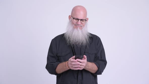 Happy Mature Bald Bearded Man Smiling While Using Phone