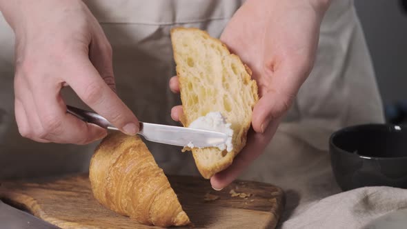 Girl or Woman or Chef Prepares Breakfast and Spreads Soft Cheese or Cream on Crispy Croissant