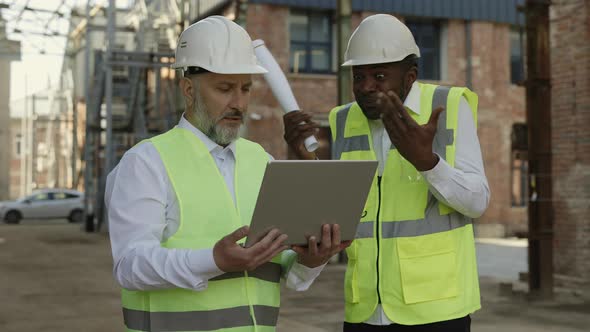 Builder Arguing with Foreman While Looking on Laptop Outdoor