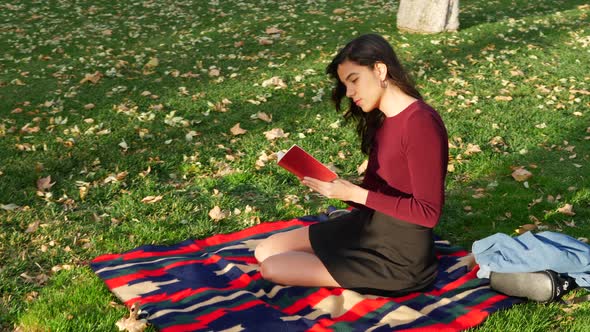 A young woman school girl reading a book on a campus lawn or outdoor park SLOW MOTION.