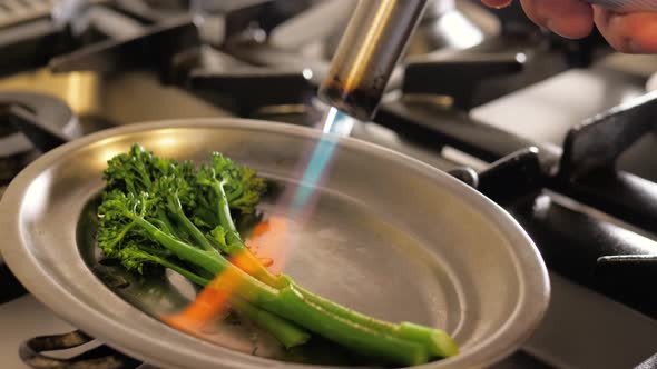 Chef Fire Vegetables Herbs Spices on Modern Kitchen in Restaurant, Cooking Burns with Fire Gun