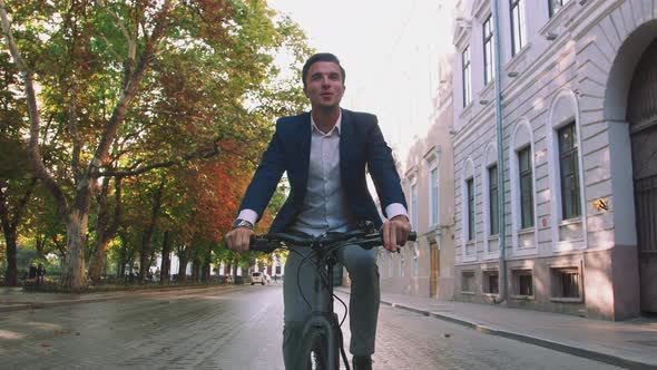 Handsome Young Man Driving His Bicycle on the Street in Park in City Center During Sunrise