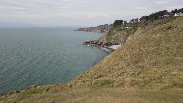 Aerial Reveal Of A Tiny Hidden Beach In Howth, Dublin, Ireland With Faraway View Of Bailey Cottage O