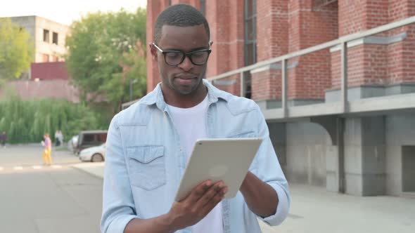 African Man Using Tablet While Walking in Street