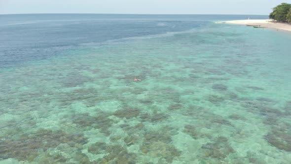 Aerial: woman snorkeling on Hatta Island coral reef tropical caribbean sea