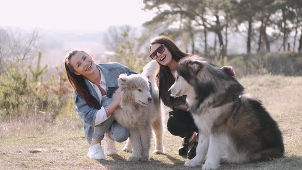 Young Beautiful Women Are Smiling and Hugging with Their Fluffy Cute Dogs