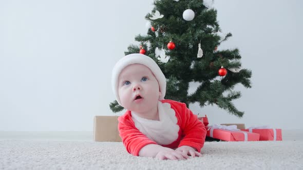 Cute Baby in Costume of Santa Claus, Looking a Gift