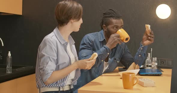 Portrait of Confident African American Man Eating Sandwich and Drinking Tea As Caucasian Woman