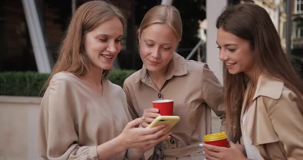 Attractive Girls Holding Paper Coffee Cups and Smiling While Standing at Street, Young Woman Using