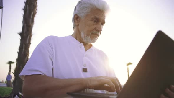 Portrait of Retirement Handsome Senior Man Using Laptop Computer on Seafront