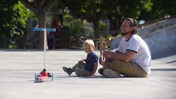 Father with His Little Blonde Son in the Skatepark