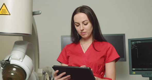 Close Up Portrait of Young Caucasian Woman Doctor in Red Uniform Holding Digital