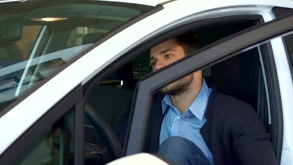 Man Sits Into the Car at the Dealership