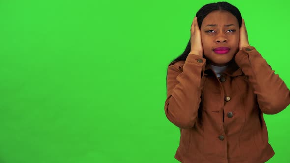 A Young Black Woman Protects Her Ears From a Loud Sound - Green Screen Studio