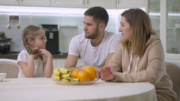 Loving Mother Giving Healthful Orange to Excited Cute Daughter Smelling Fruit and Smiling