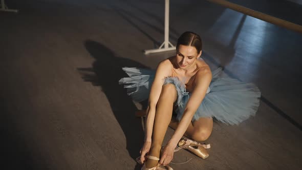 High Angle View of Concentrated Confident Slim Ballerina Tying Pointe Shoes Sitting on Floor in