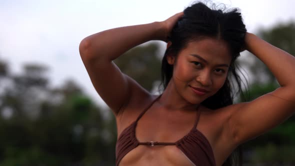 Beautiful Young Woman Looking At Camera On Beach At Sunset