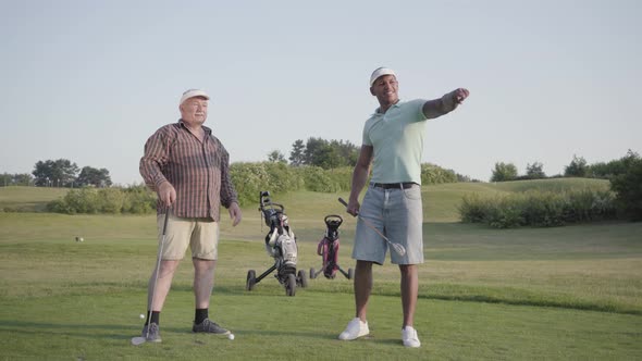 Mature Caucasian Man and Young Middle Eastern Man Playing Golf on the Golf Course
