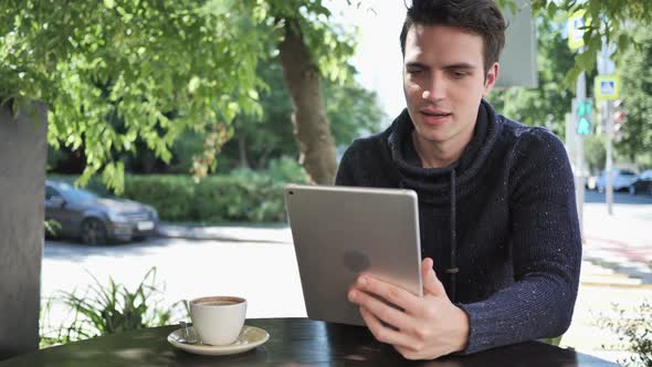 Excited Man Celebrating Success on Tablet Sitting in Cafe Terrace