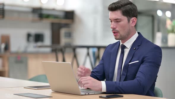 Sick Businessman with Laptop Coughing in Office 