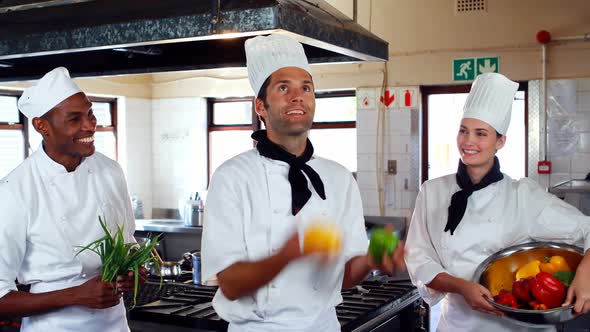 Head chef juggling vegetables and colleagues watching