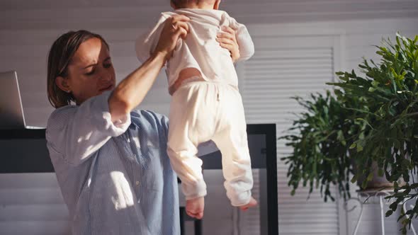 A Young Mother is Working at Home Using Computer While She's Taking Care of Her Baby