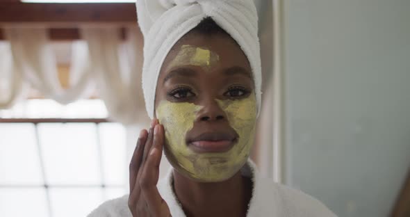 Portrait of african american attractive woman applying face mask in bathroom