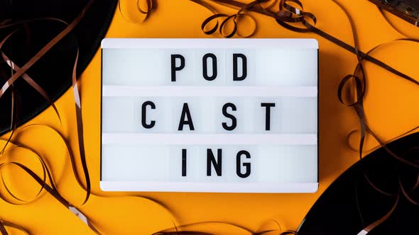 Podcasting Lettering and Vinyl Record Album Audio Cassette Tape on Yellow Background