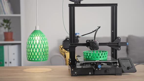 Modern Technologies Automatic 3D Printer Prints From Molten Green Plastic a Prototype of a Lamp