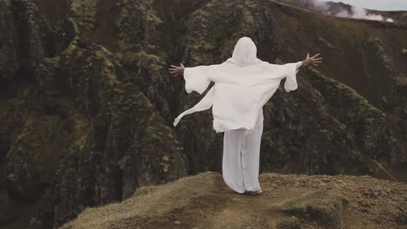 Person Wearing White Hooded Robe Spreads Hands to Feel the Breeze