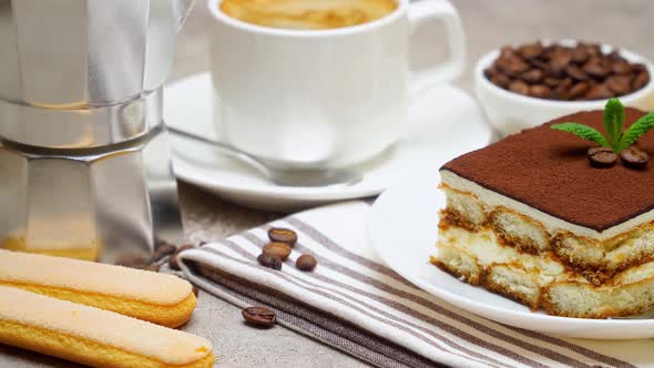Portion of Traditional Italian Tiramisu dessert, mocha coffee maker, cup of espresso on white