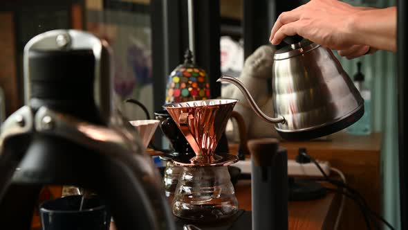 The barista is brewing coffee with traditional drip brewing equipment.