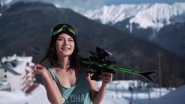 Portrait of Young Asian Woman in Blue Swimsuit Standing with a Pair of Ski at Winter Resort at Snowy