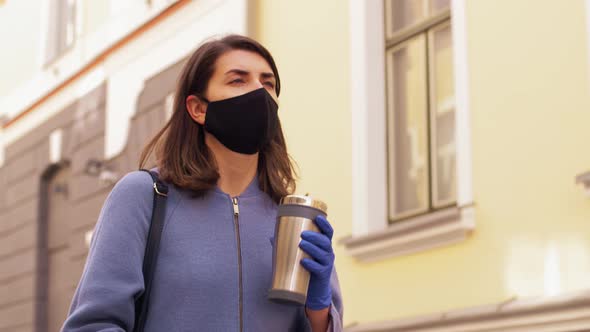 Woman in Mask with Tumbler Walking in City