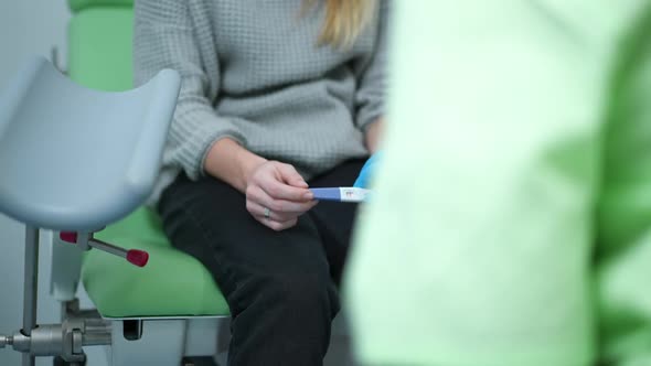 Unrecognizable Teenage Caucasian Girl with Positive Pregnancy Test Sitting on Gynecological Chair in