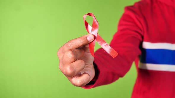 Hand Holding Red HIV Ribbon Against Green Screen 