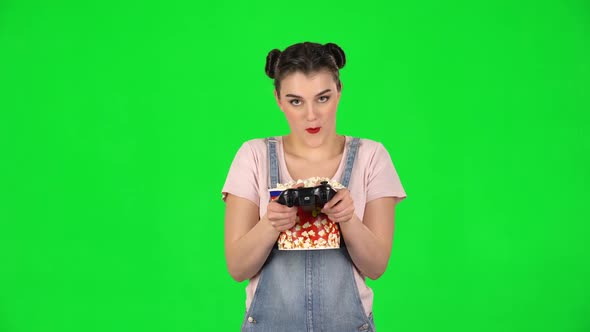 Girl Playing a Video Game and Chews Popcorn on a Green Screen