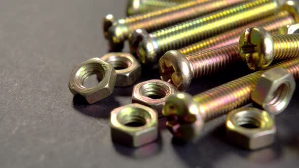 Shiny metal bolts and nuts on dark paper. A set of threaded hardware for fastening. Mechanical tools