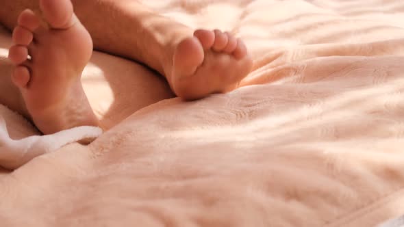 Close Up of the Legs of a Man Who is Lying in Bed and Can Not Sleep