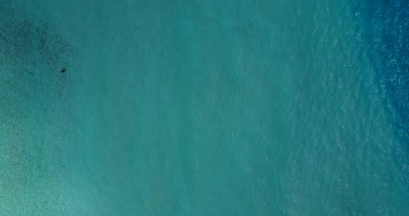 Beautiful aerial travel shot of a sandy white paradise beach and aqua blue ocean background in 4K