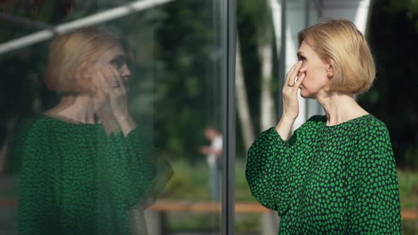 Side View Caucasian Woman Standing Outdoors Looking at Reflection in Glass Building