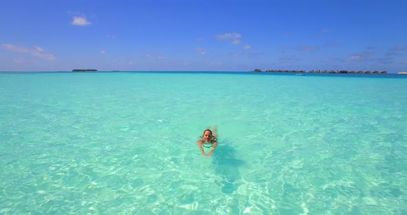 Aerial drone view of a woman floating and swimming on a tropical island