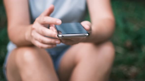 Close Up of Young Woman Hands Using and Holding Smart Phone Scrolling Up and Down on Touchscreen