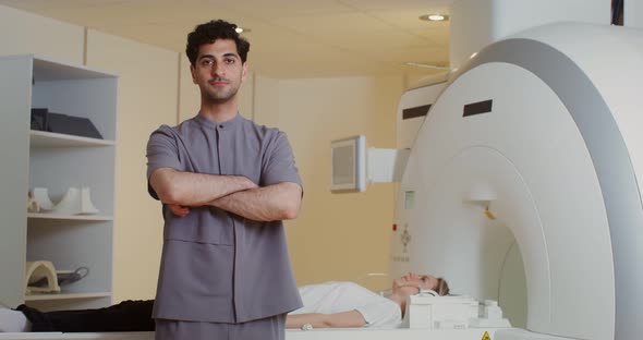 A Doctor Looks Into the Camera Standing in Front of an MRI Machine