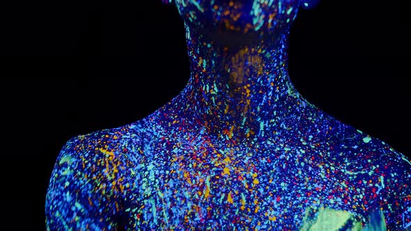 Man Painted with Fluorescent Paints Runs Thumb Over Neck Front View