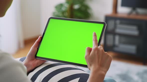 Woman holding in hands a digital tablet with green screen for internet online.